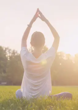 A peaceful person sitting in meditation, surrounded by nature, fully present in the moment, radiating calm and awareness.